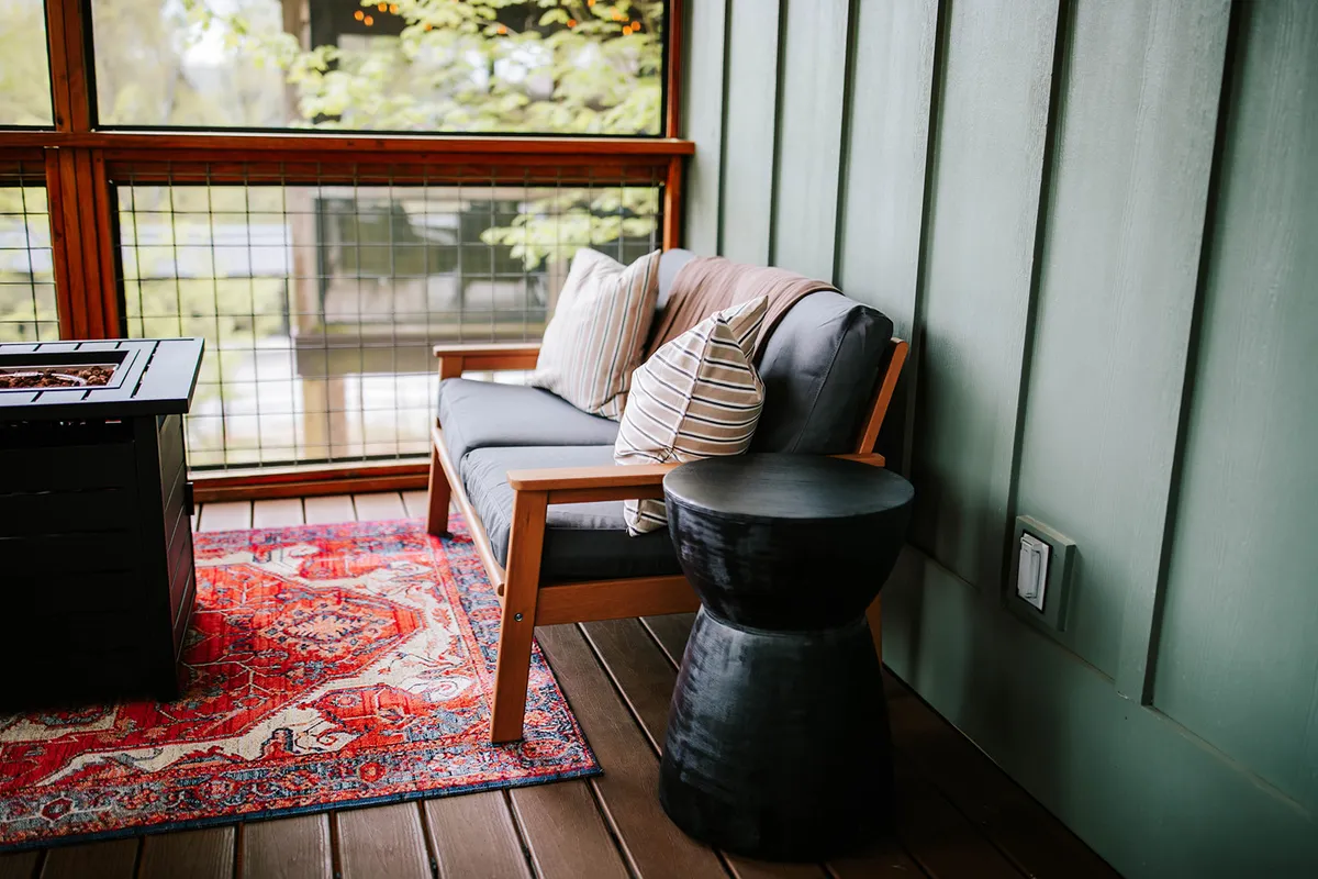 A comfortable outdoor seating area featuring a sofa arranged around a modern fire pit, with a textured rug and a side table. The space is designed for relaxation and socializing, with the open air and the fire pit inviting guests to unwind after a day of exploration.