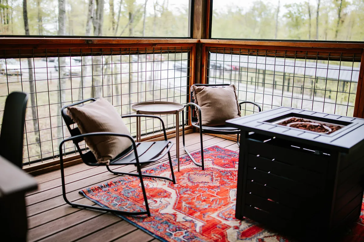A cozy fire pit lounge with comfortable chairs arranged on a rug, creating an intimate spot for relaxing or socializing. Surrounded by natural textures and soft light, the scene suggests evenings spent together, perhaps after a day of celebration or exploration.
